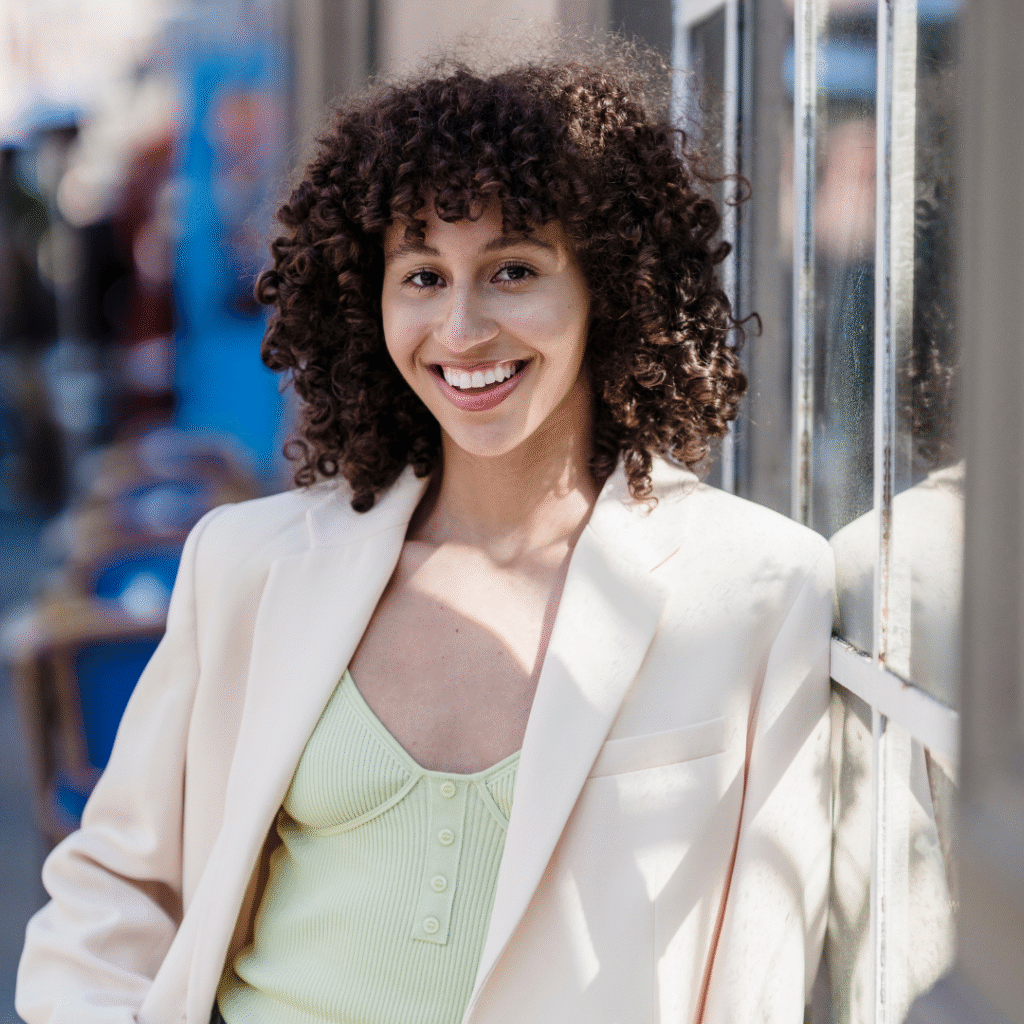 woman smiling at the camera, leaning on a wall